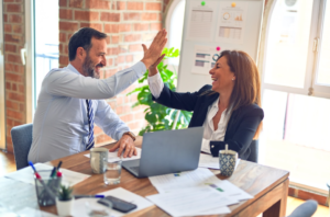 Two business professionals high-five after using Pareto chart data to make an informed decision